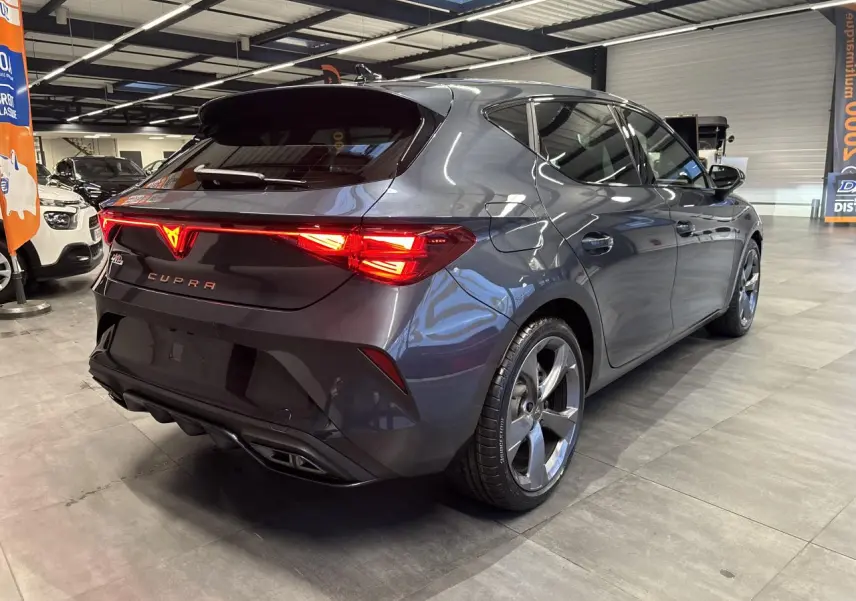 Vue 3/4 arrière droite d'une CUPRA Leon gris magnetic avec feux arrière Tri-LED et double sortie d'échappement noire.