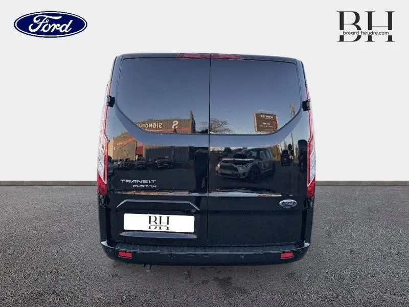 Vue arrière d'un Ford Transit Custom noir Agate métallisé avec portes battantes et logo Ford visible.