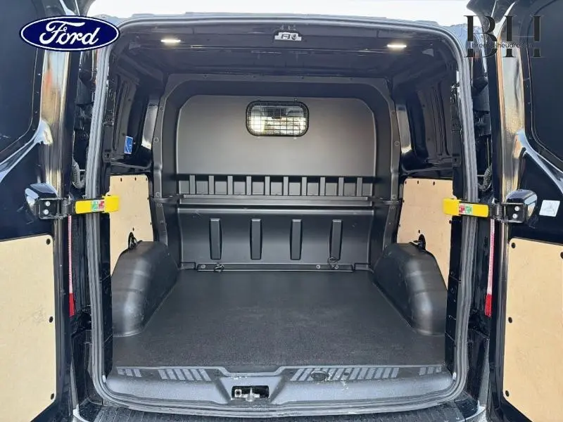 Vue arrière intérieure du Ford Transit Custom noir Agate métallisé, montrant l’espace de chargement vide avec portes battantes ouvertes.