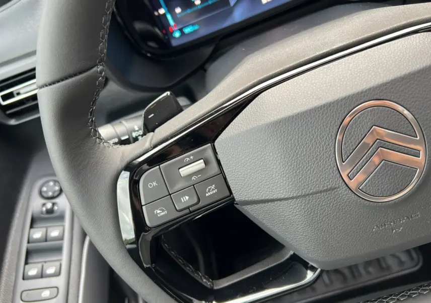 Gros plan sur le volant cuir multifonctions côté gauche du Citroën Berlingo 2025, avec commandes intégrées et logo central.