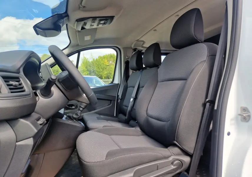Vue intérieure côté conducteur du Renault Trafic blanc 2026, montrant les sièges avant noirs et le volant.