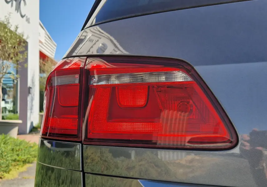 Gros plan sur le feu arrière droit d’une Volkswagen Golf Sportsvan gris Indium Metal, soulignant la finition et la teinte métallique.