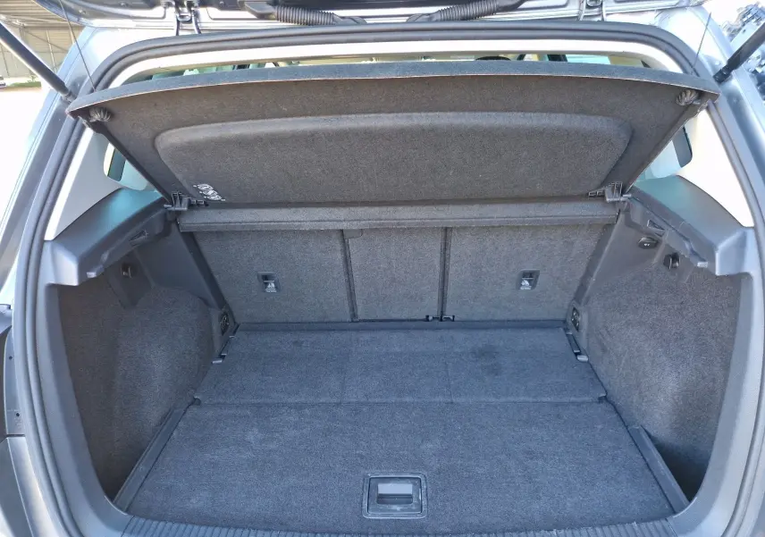 Coffre ouvert vu de l'arrière d'une Volkswagen Golf Sportsvan gris Indium Metal, montrant un espace de chargement spacieux et propre.