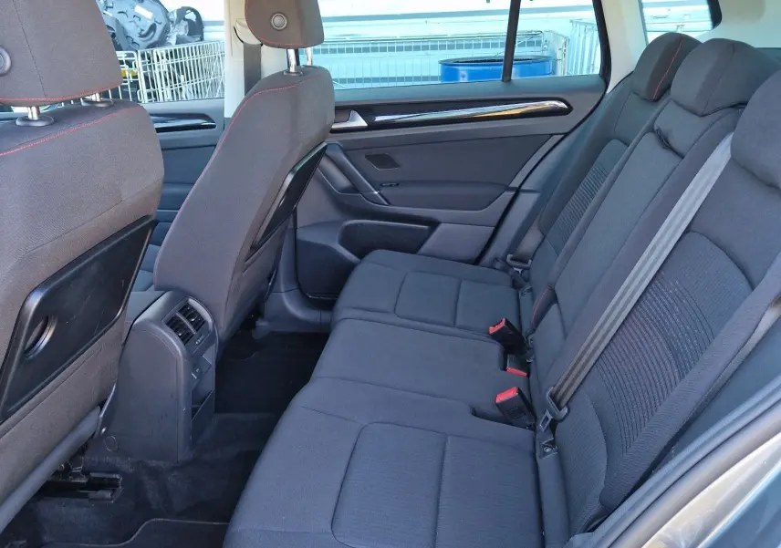 Vue intérieure côté droit des sièges arrière gris foncé avec surpiqûres rouges d'un Volkswagen Golf Sportsvan 2017 gris Indium Metal.
