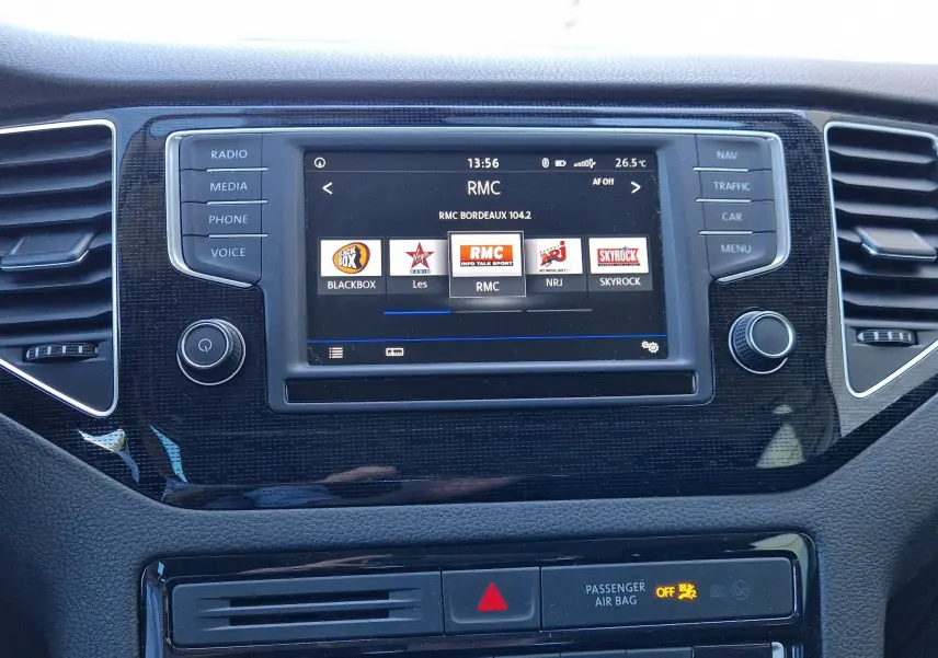 Vue rapprochée de l’écran multimédia central du Volkswagen Golf Sportsvan gris Indium, affichant les stations radio.