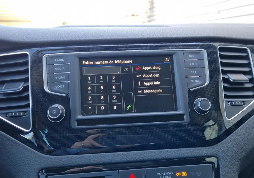 Vue rapprochée de la console centrale de la Volkswagen Golf Sportsvan 2017, écran tactile affichant le menu téléphone, entouré de boutons noirs.