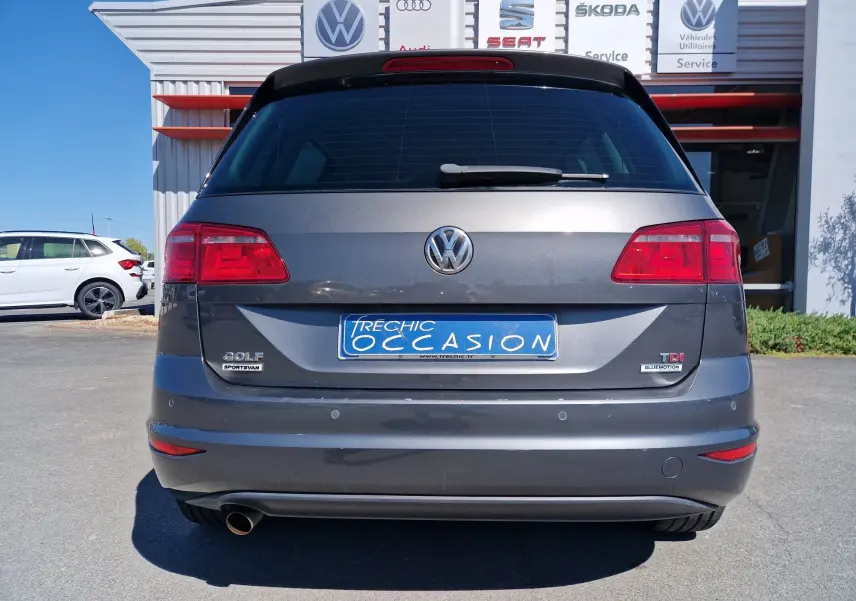 Vue arrière d'un Volkswagen Golf Sportsvan gris Indium Metal de 2017, avec logo VW et plaques d'occasion visibles.