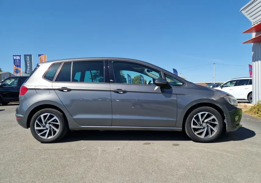 Vue de profil côté gauche d'une Volkswagen Golf Sportsvan gris Indium métallisé, avec jantes alliage et vitres teintées.