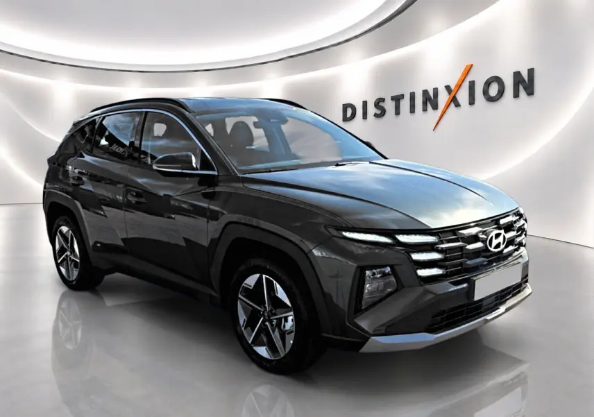 Vue 3/4 avant d'un Hyundai Tucson vert foncé avec jantes alliage et calandre distinctive dans un showroom lumineux.