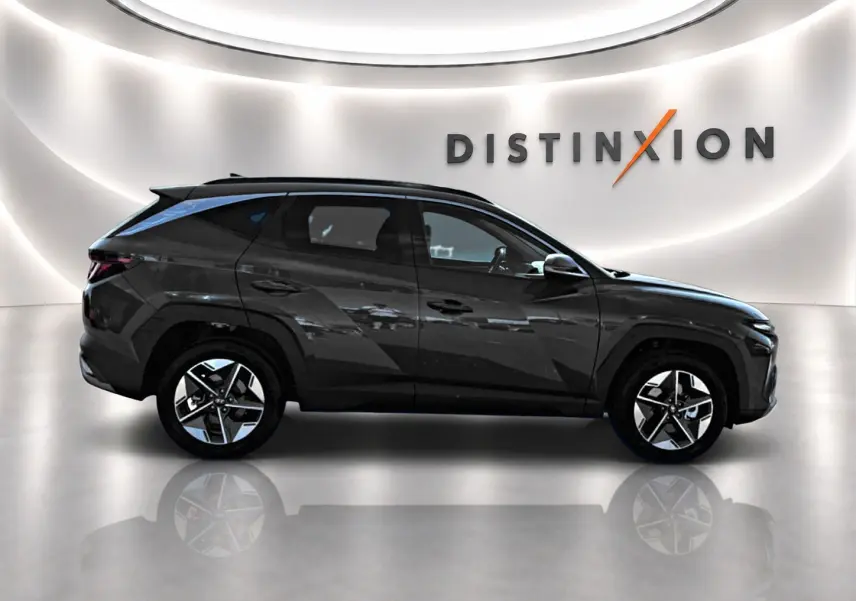 Vue de profil côté gauche d'un Hyundai Tucson vert foncé avec jantes alliage et lignes anguleuses marquées.
