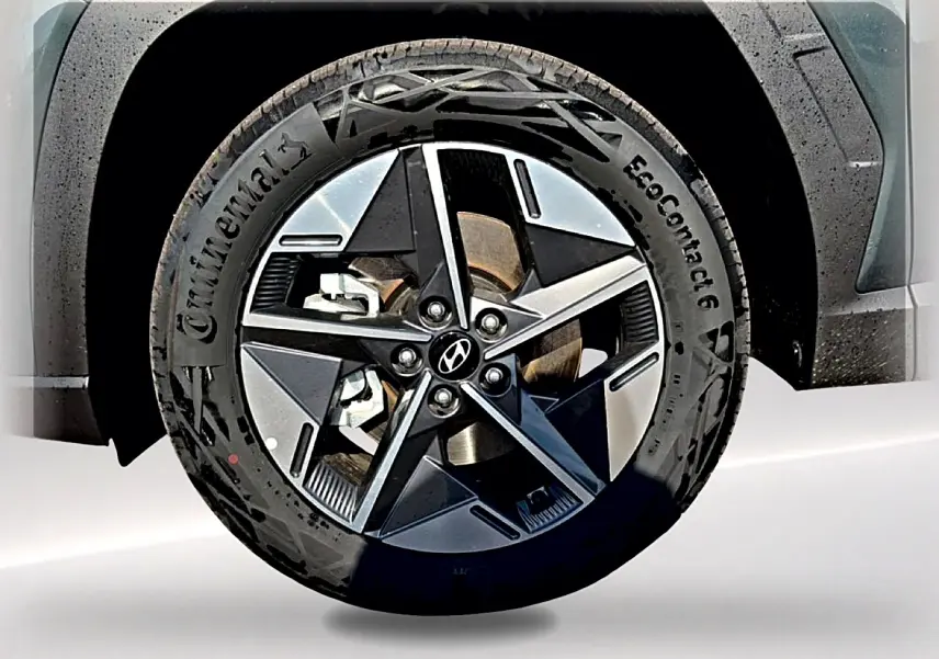 Gros plan sur la jante alu 18 pouces noire et grise d’un Hyundai Tucson vert, avec logo Hyundai au centre.