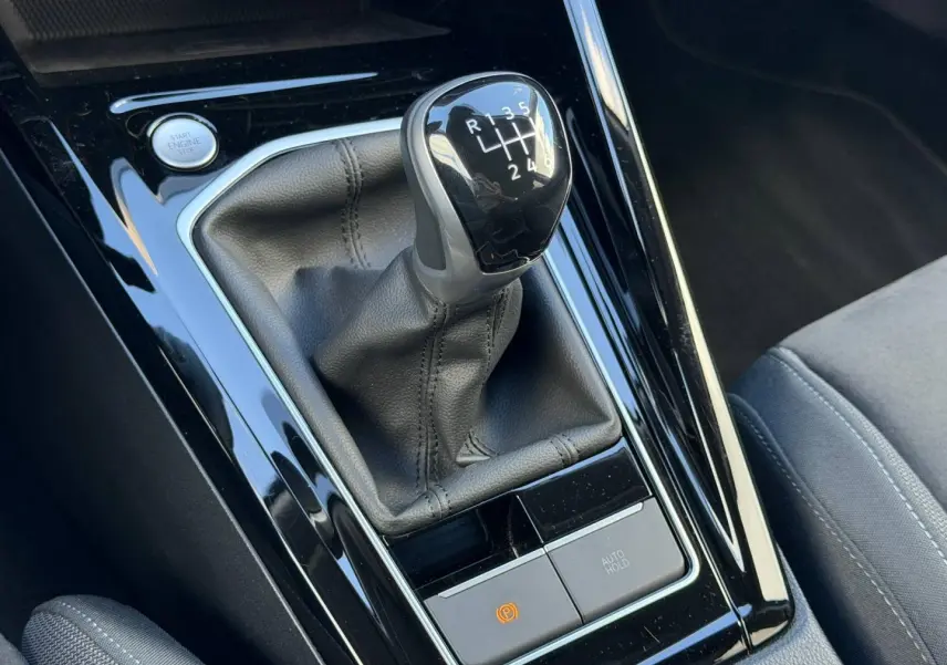 Gros plan sur le levier de vitesses manuel noir et la console brillante d'une Volkswagen Golf 2024 gris lunaire.