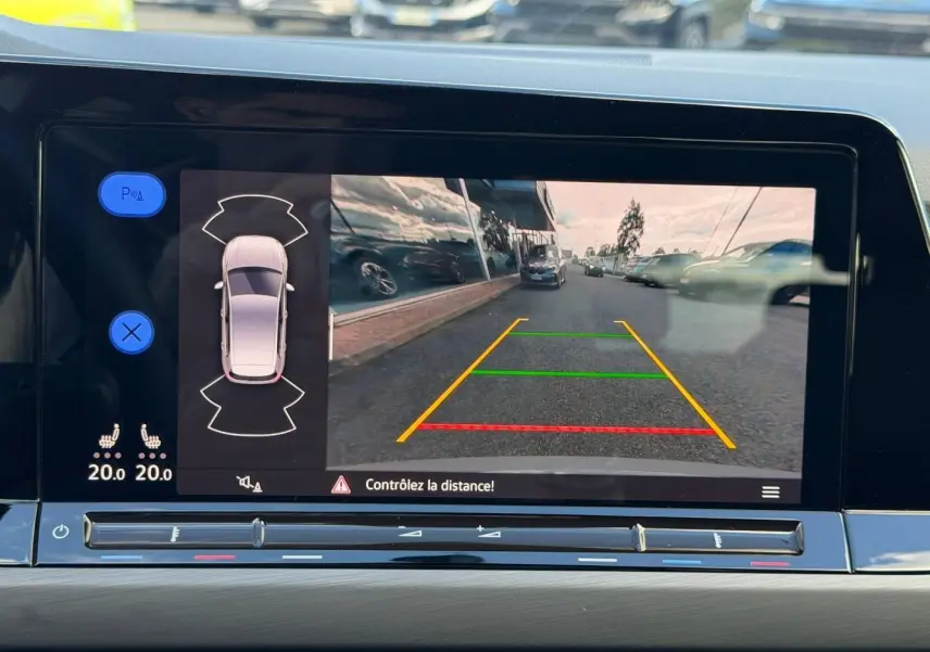 Écran tactile intérieur montrant la caméra de recul et l’aide au stationnement d’une Volkswagen Golf gris lunaire.