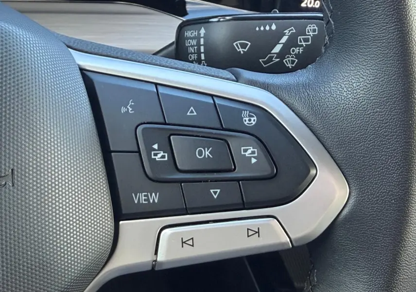 Gros plan sur les commandes multifonctions noires et argent du volant cuir de la Volkswagen Golf gris lunaire 2024.