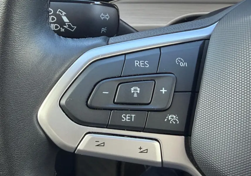 Gros plan sur les commandes du volant cuir noir de la Volkswagen Golf 2024, boutons de régulateur de vitesse et assistance.