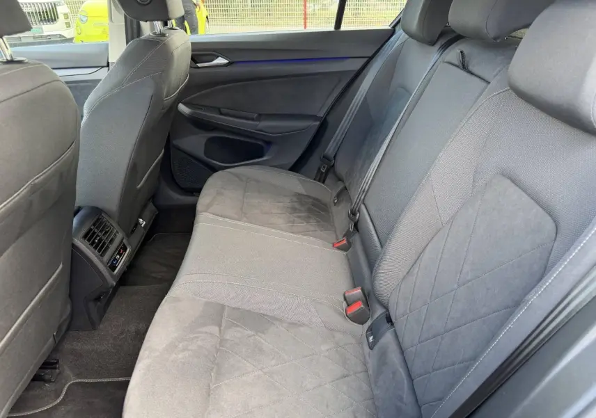 Vue intérieure de la banquette arrière grise de la Volkswagen Golf 1.5 TSI 2024 avec accoudoir central et aérations arrière.