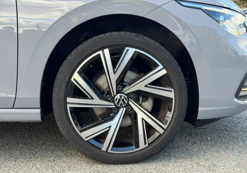 Gros plan sur la roue avant droite d'une Volkswagen Golf gris lunaire avec jante alliage au design moderne.