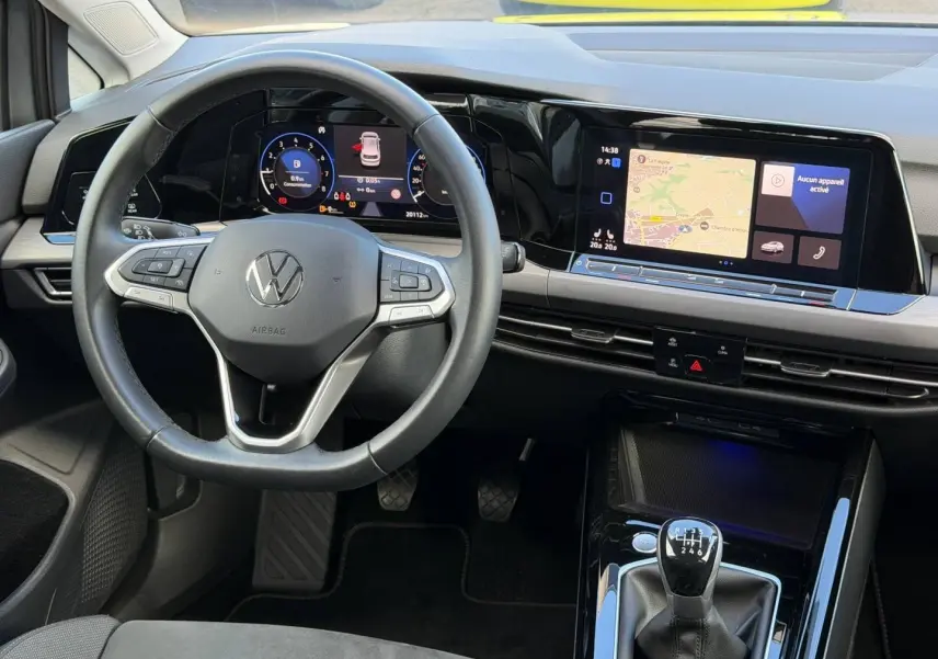 Vue intérieure avant de la Volkswagen Golf 2024, volant cuir multifonction et écran tactile avec navigation visible.