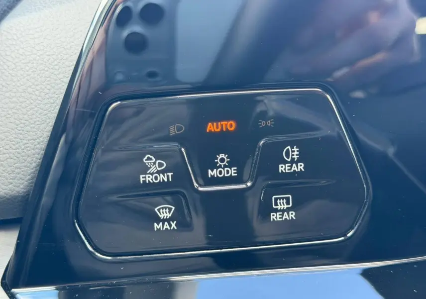 Gros plan sur les commandes d’éclairage et désembuage en plastique noir brillant dans l’habitacle d’une Volkswagen Golf gris lunaire.