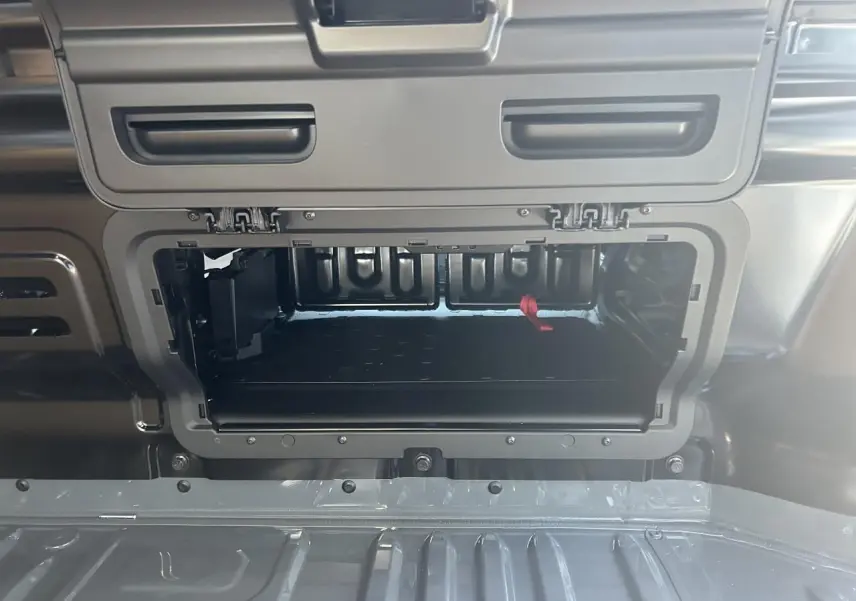 Gros plan sur la trappe de cloison ouverte du Renault Trafic Fourgon gris urbain, montrant l'espace de rangement intérieur.