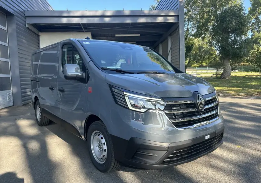 Renault Trafic Fourgon gris urbain en 3/4 avant droit, avec calandre chromée et caméra de recul visible.