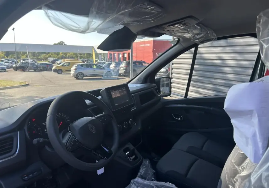 Intérieur du Renault Trafic Fourgon 2025 vu côté conducteur, avec tableau de bord moderne et sièges noirs.