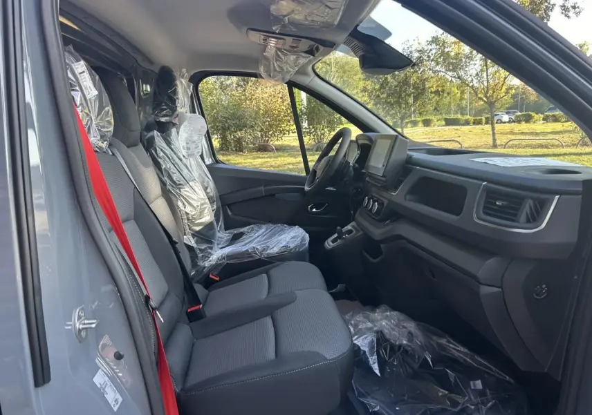 Intérieur côté conducteur du Renault Trafic Fourgon gris urbain 2025, avec sièges protégés et tableau de bord moderne.