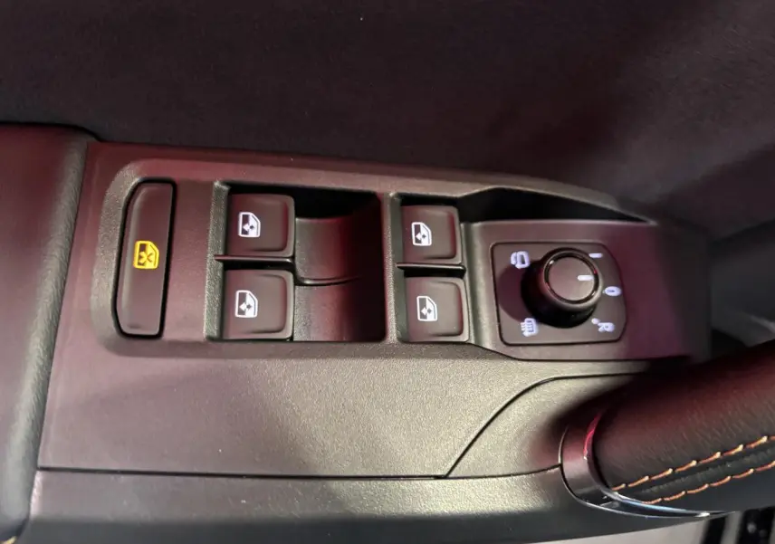 Gros plan sur les commandes de lève-vitres et rétroviseurs côté conducteur d'une CUPRA Leon noir midnight.
