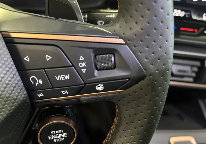 Gros plan sur le volant perforé noir avec commandes cuivrées et bouton Start Engine Stop d'une CUPRA Leon 2026.
