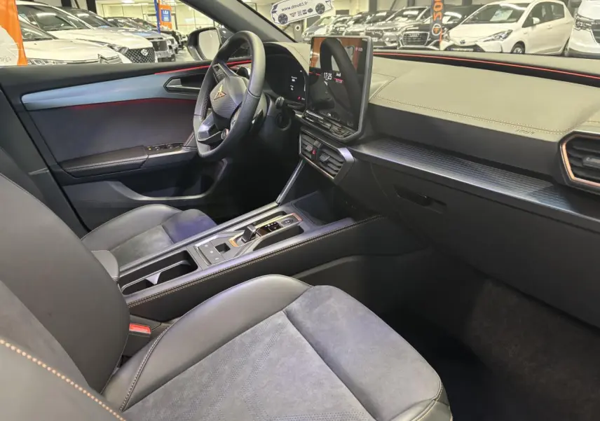 Vue intérieure côté conducteur de la CUPRA Leon 2026 noir midnight, avec tableau de bord texturé et surpiqûres cuivrées.