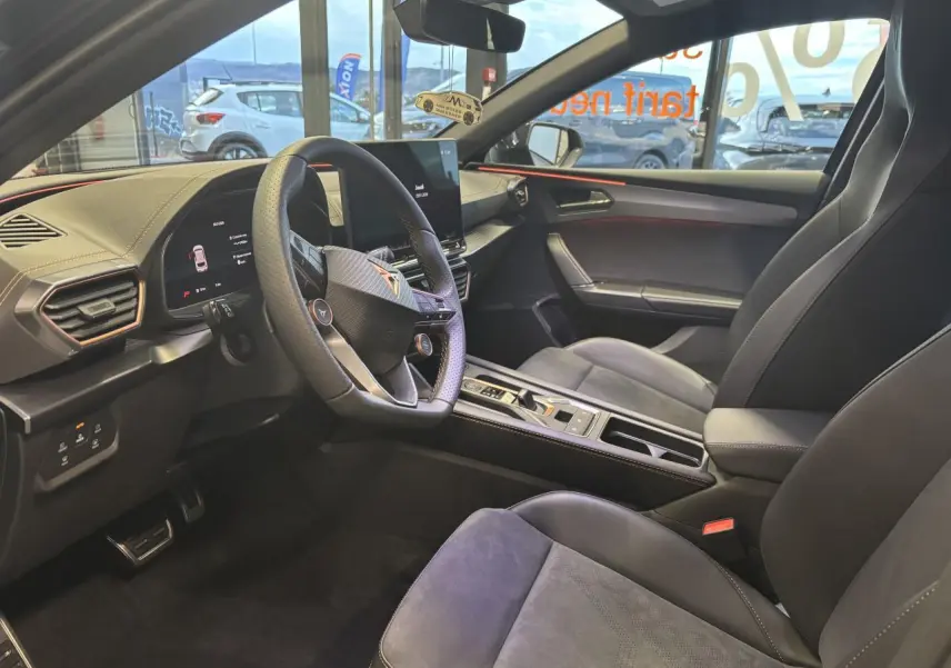 Intérieur avant droit de la CUPRA Leon noir midnight, volant cuir perforé et sièges baquets suédine avec surpiqûres cuivrées.