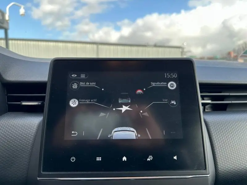 Écran tactile central de la Renault Clio 2023 gris, affichant les aides à la conduite avec ciel bleu en arrière-plan.