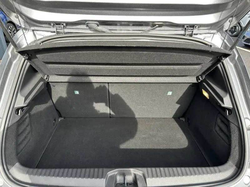 Vue plongeante sur le coffre ouvert d'une Renault Clio gris 2023, montrant un espace de rangement propre et vide.