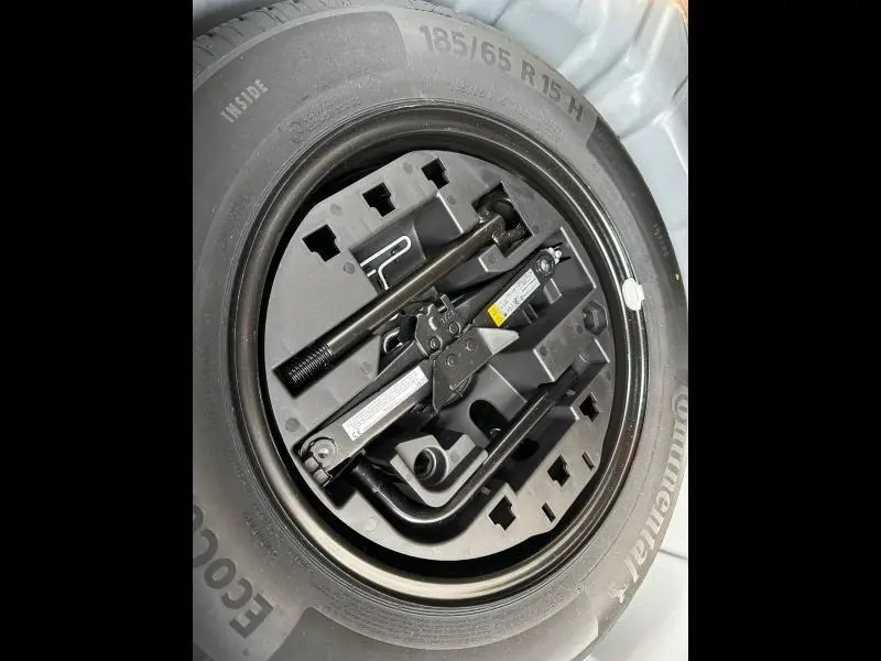 Gros plan sur la roue de secours avec kit d’outils intégré dans le coffre d’une Renault Clio gris 2023.