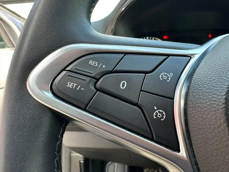 Gros plan sur les commandes du régulateur de vitesse au volant côté gauche d’une Renault Clio gris 2023.