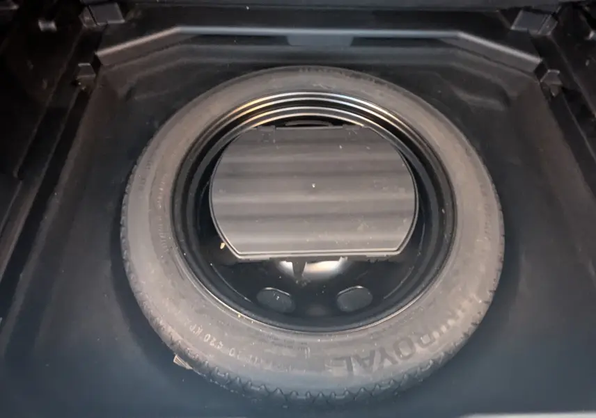 Vue rapprochée de la roue de secours noire dans le coffre d'un Peugeot 3008 blanc toit noir HDi 130 Allure 2018.