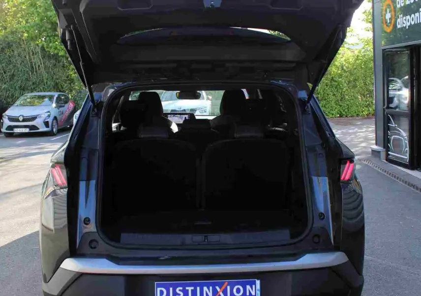 Vue arrière d'un Peugeot 5008 gris titane métallisé 2025 avec hayon ouvert, montrant l'espace de coffre.