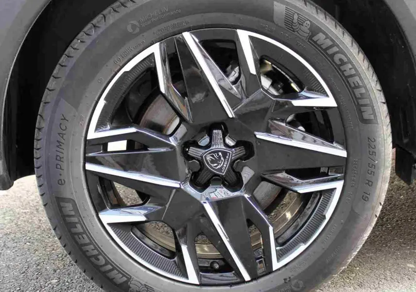 Gros plan sur la jante alliage noire et argentée du Peugeot 5008 III Hybrid gris titane, avec pneu Michelin 225/55 R19.