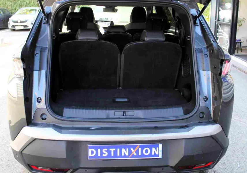 Vue arrière du Peugeot 5008 gris titane métal 2025 avec coffre ouvert et sièges arrière visibles.