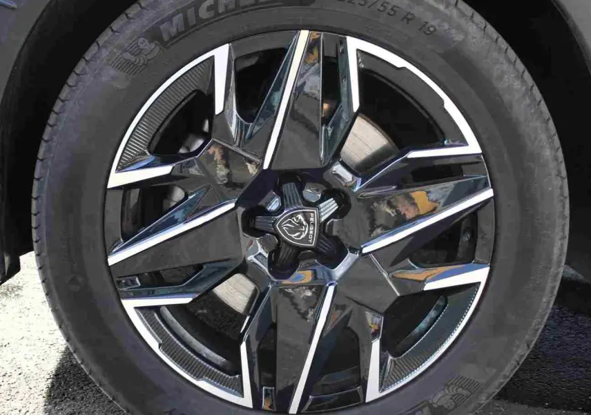 Gros plan sur la jante alliage noire et argentée du Peugeot 5008 gris titane, mettant en valeur le logo central et le pneu Michelin.