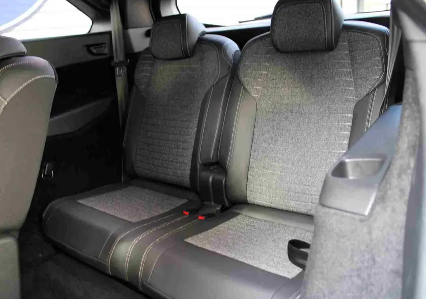 Vue intérieure arrière droite des sièges gris tissu et cuir du Peugeot 5008 Hybrid 2025, finition Allure avec surpiqûres contrastées.