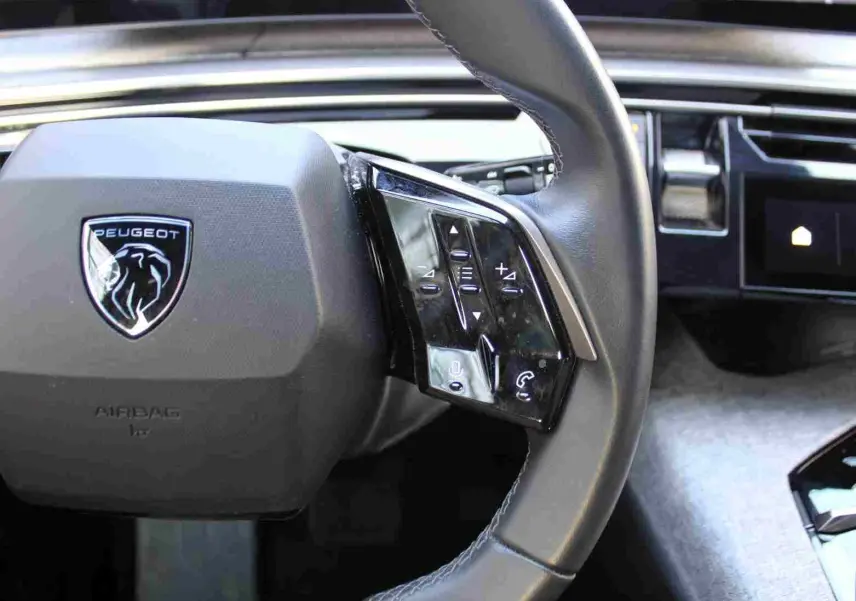 Gros plan sur le volant cuir noir du Peugeot 5008 2025 avec commandes intégrées et logo lion au centre.