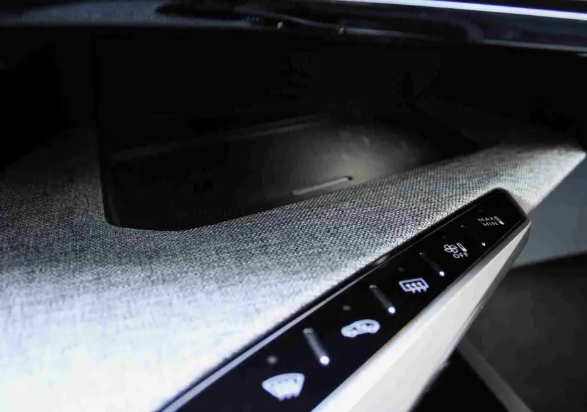 Détail du tableau de bord avec commandes tactiles éclairées sur tissu gris clair du Peugeot 5008 Hybrid 2025.