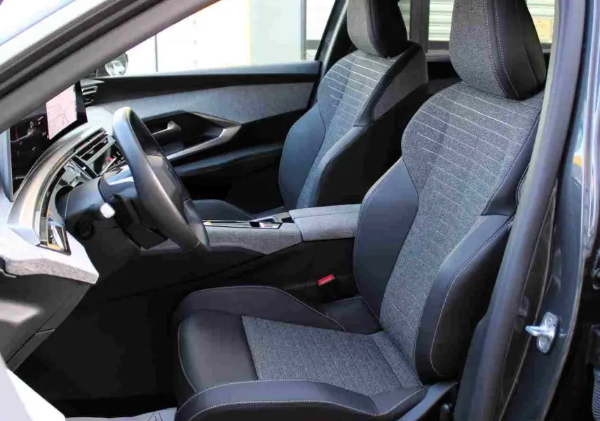 Vue intérieure côté conducteur du Peugeot 5008 gris titane, mettant en valeur les sièges bi-matière gris et noir avec surpiqûres contrastantes.