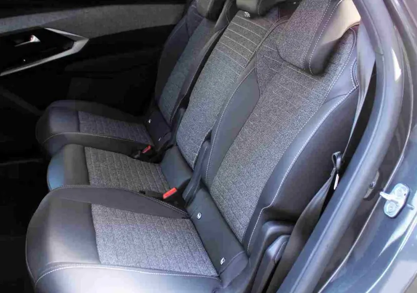 Vue latérale des sièges arrière en tissu gris et cuir noir du Peugeot 5008 gris titane, avec ceinture et appuie-têtes visibles.