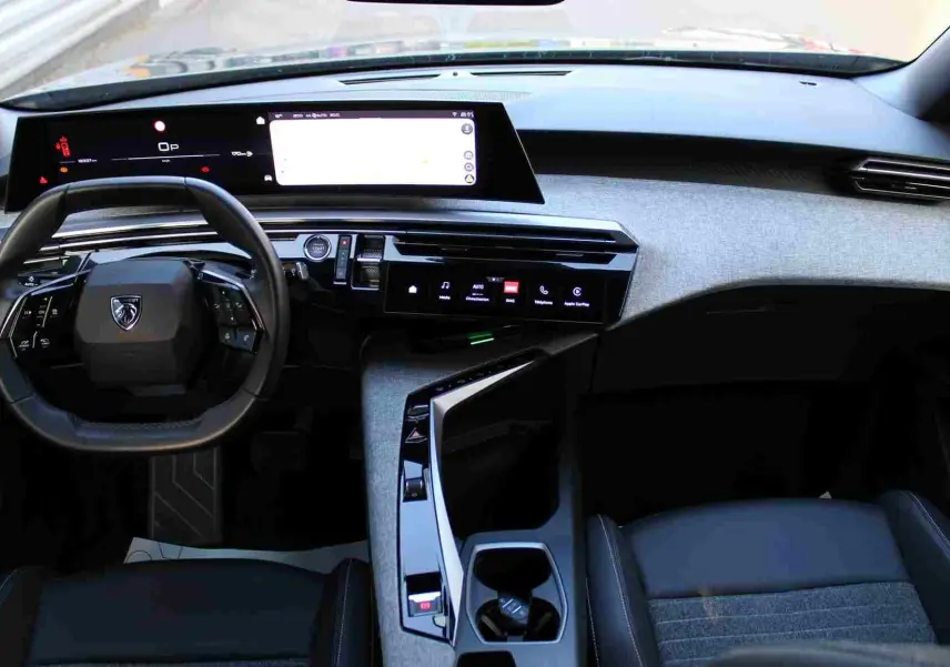 Vue intérieure du tableau de bord et volant du Peugeot 5008 hybride 2025 avec finition gris noir et écran tactile large.