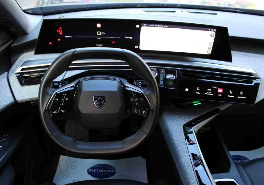 Vue intérieure frontale du tableau de bord et volant noir du Peugeot 5008 Hybrid 2025 avec écrans numériques larges.