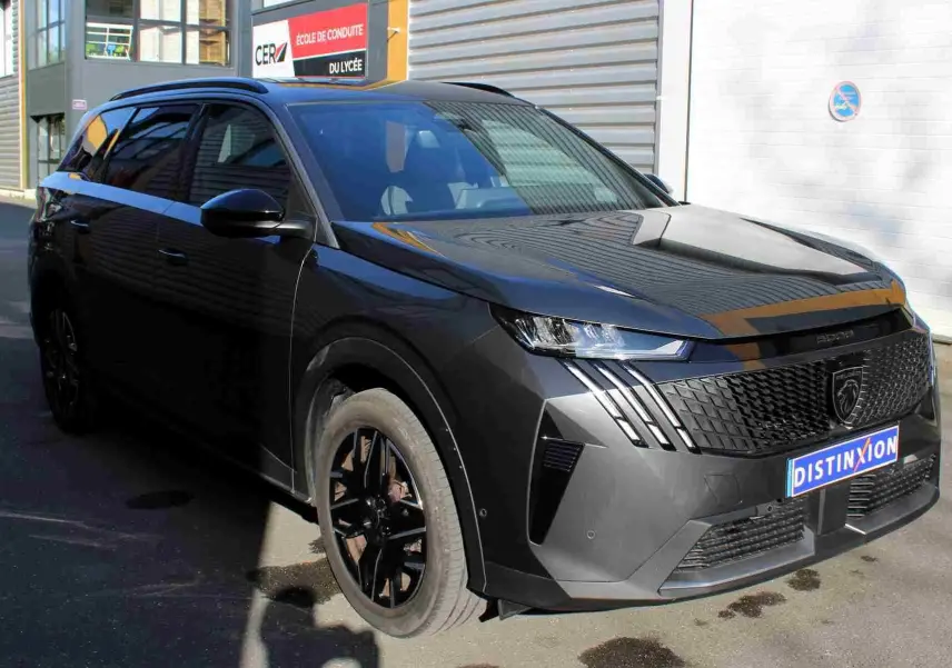 Peugeot 5008 gris titane métal en 3/4 avant droit, avec calandre noire et jantes noires distinctives.