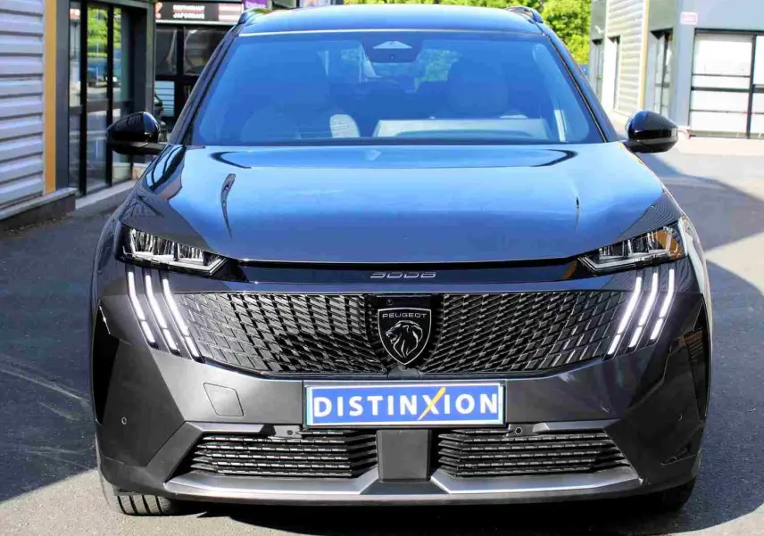 Vue de face du Peugeot 5008 gris titane métal 2025 avec calandre noire et feux LED verticaux allumés.