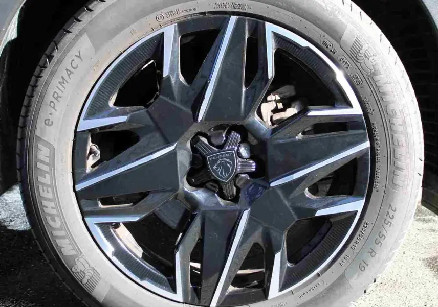 Gros plan sur la jante alliage noire et argentée du Peugeot 5008 gris titane, avec logo lion au centre.